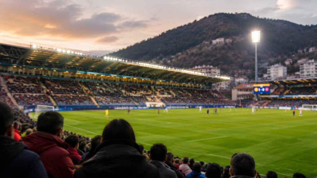 Moneda con los escudos del Eibar y el Almería sobre un campo de fútbol