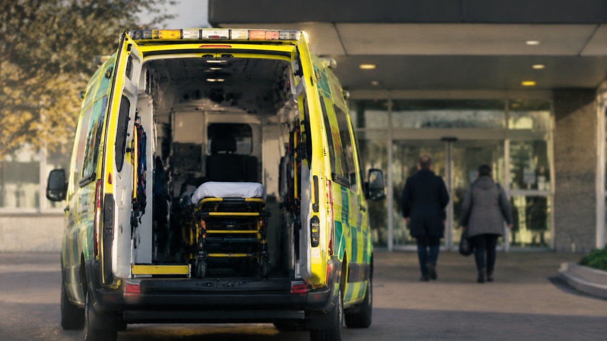 Acceso a un hospital en Toledo con una ambulancia y personas vistas de espaldas