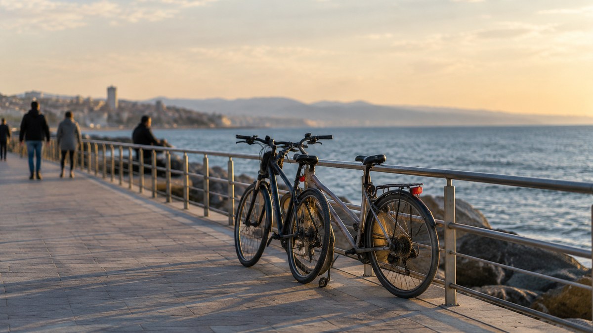 Bicicletas junto a un paseo marítimo con figuras anónimas al fondo.